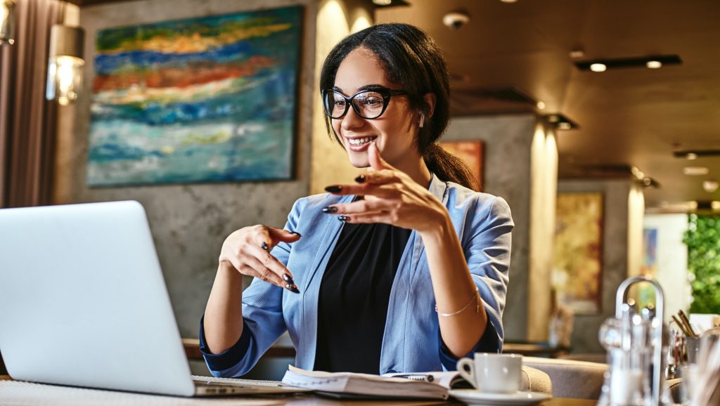Young businesswoman sitting in cafe in front of laptop and networking